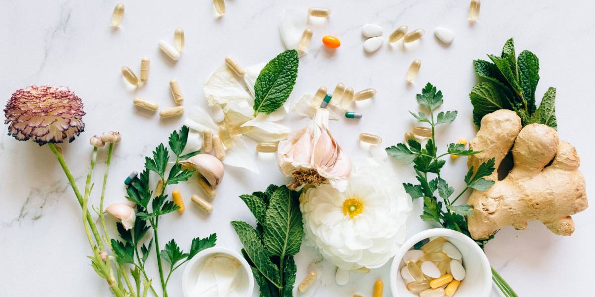 Médecine naturelle: plantes, fleurs, racines, capsules, comprimés, sur table de marbre blanche